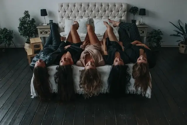 Women lying across a stylish hotel bed at the best hotels for girls' trip