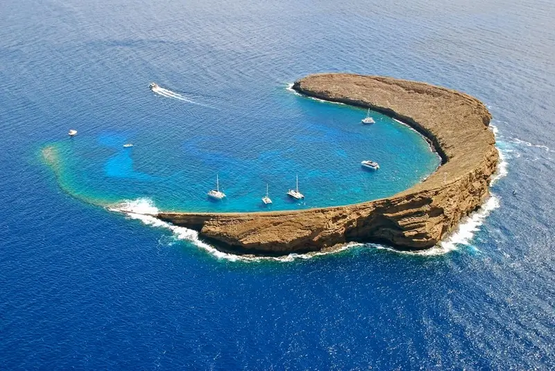 aerial view of Molokini Crater with sailboats anchored inside the crescent-shaped reef in Hawaii
