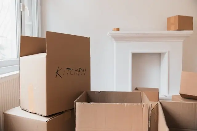 labeled kitchen moving box among stacked cardboard boxes in a bare room ready for moving day