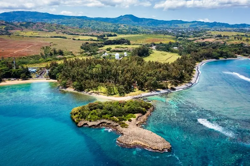Aerial view of Poste Lafayette on the East Coast of Mauritius with turquoise waters, volcanic rock formations and rolling green hills inland