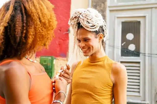 two women smiling and holding hands outdoors in a colorful urban setting
