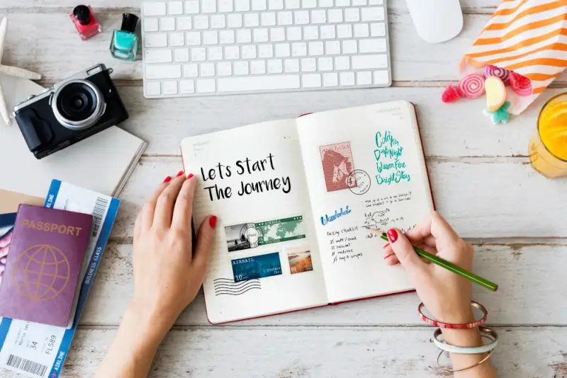 A travel journal with handwritten notes and stamps next to a passport, camera, and boarding passes — planning the next trending travel destinations for your bucket list