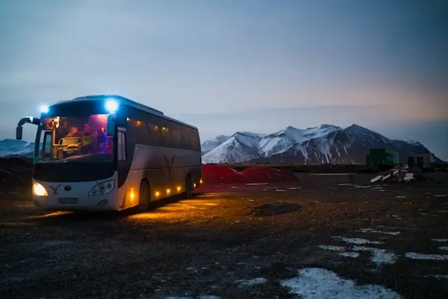Private coach bus transporting a group at dusk with snowy mountains in the background