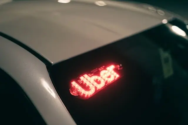 A glowing red Uber logo on the roof of a rideshare vehicle at night, highlighting how transportation companies operate under passenger safety obligations