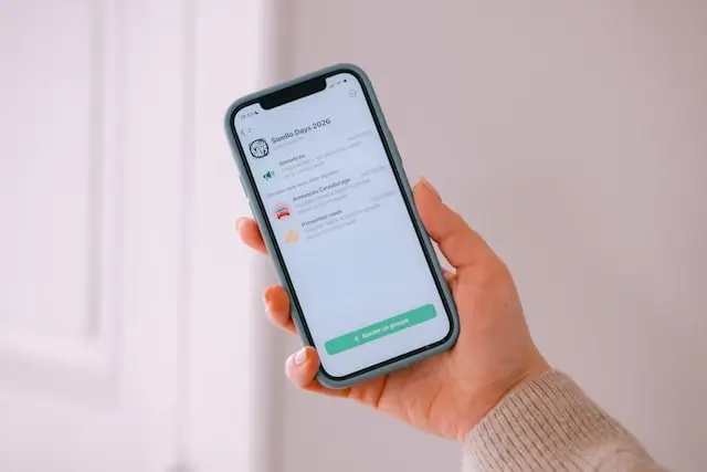 Hand holding a smartphone with a group chat app open for trip communication