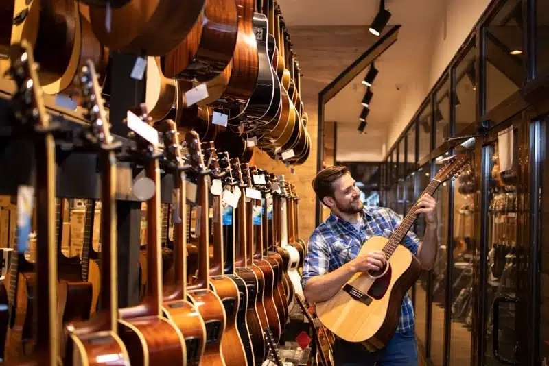 man trying a guitar in a music store before buying