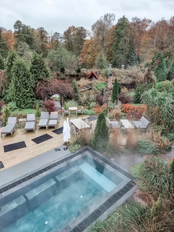 Outdoor heated pool and loungers surrounded by autumn foliage at Åstad Vingård spa retreat in Sweden