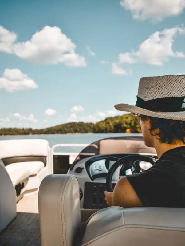 Person at the helm of a modern boat with a smart navigation console on a sunny lake
