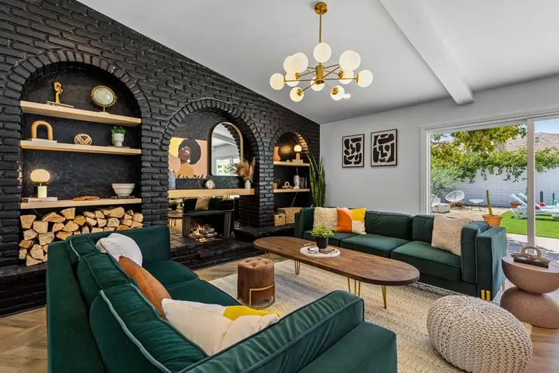 Stylish Autograph Collection hotel living room with green velvet sofas and black brick fireplace