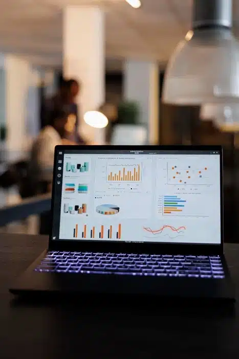 laptop screen showing digital marketing analytics and performance charts in a modern office setting