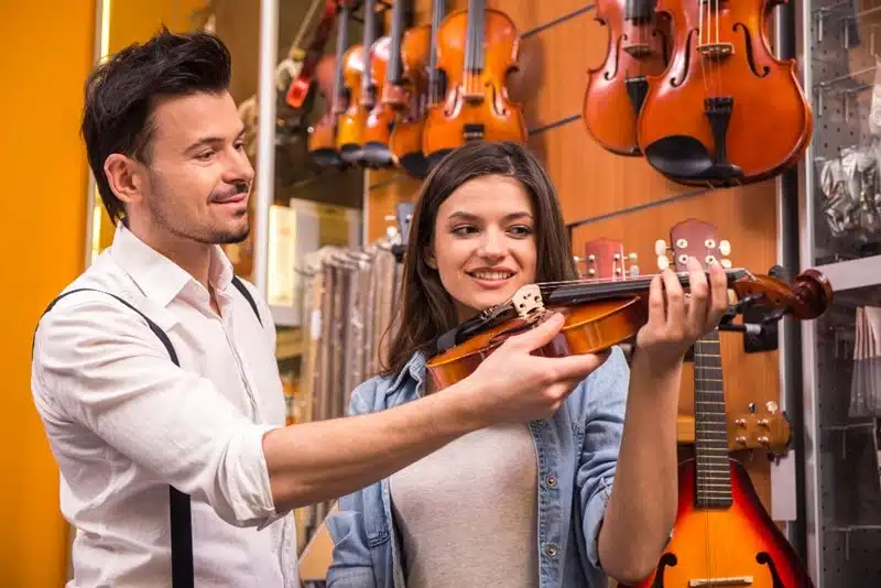 music store expert helping a woman try a violin
