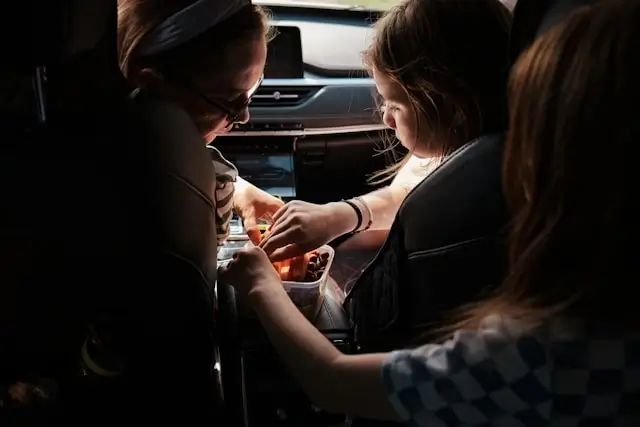 kids sharing snacks inside a car during a road trip