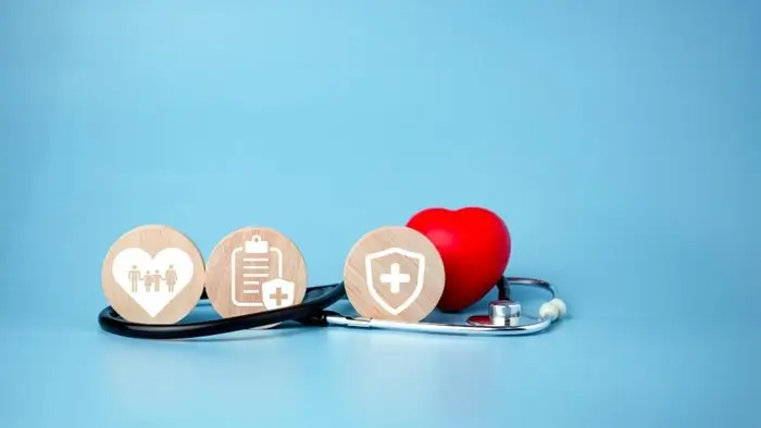 health and travel insurance in India concept with wooden icons, stethoscope, and red heart on blue background
