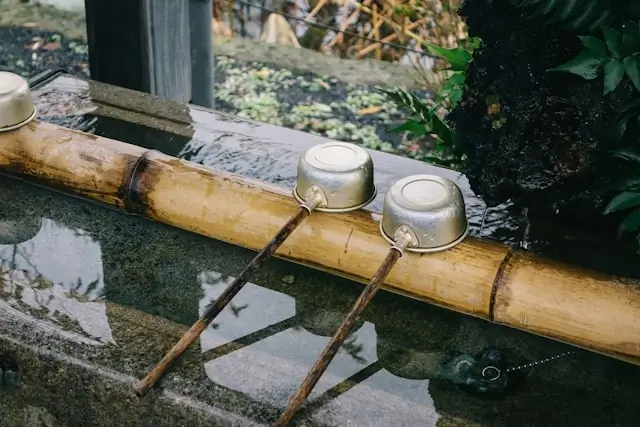 Traditional bamboo water fountain with metal ladles at a Japanese onsen hot spring