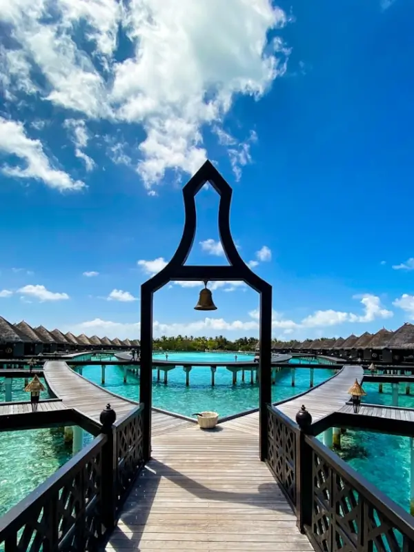 Wooden boardwalk leading to overwater bungalows over turquoise lagoon at a luxury wellness resort in the Maldives