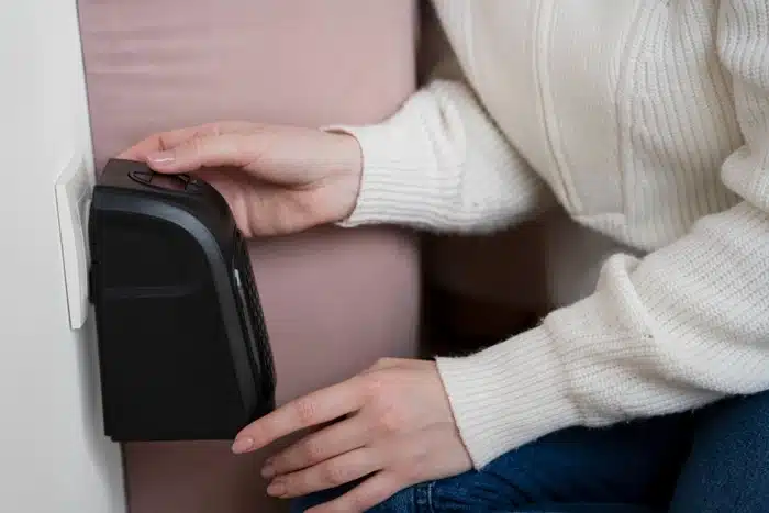 Woman installing a portable door lock on a door hinge for added security while traveling