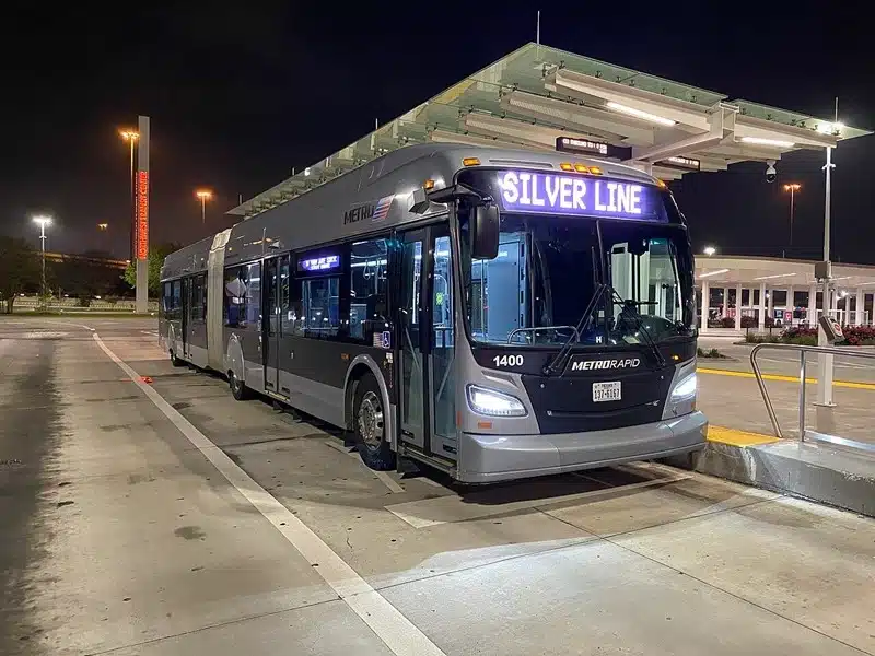 Houston MetroRapid Silver Line articulated bus stopped at a transit station after dark