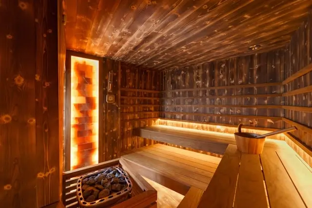 Warm wooden sauna interior with Himalayan salt wall and ambient lighting for a relaxing wellness experience