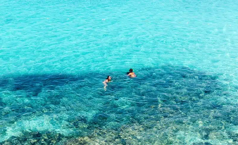 Two people snorkeling in the crystal-clear turquoise waters of Ibiza on a sunny day