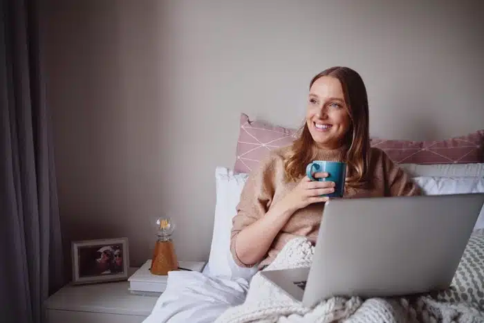 woman relaxing at home on the weekend with laptop and coffee