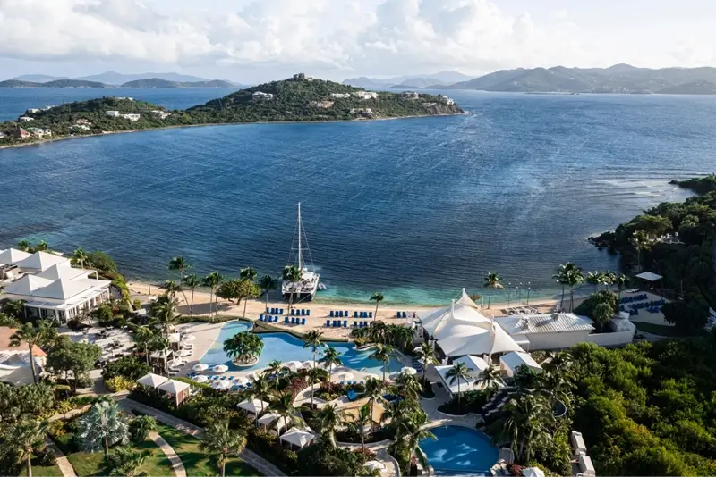 Aerial view of St. Regis resort with pools, palm trees and turquoise bay surrounded by islands