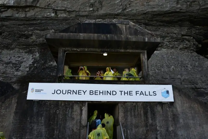 visitors in yellow ponchos entering the attraction entrance carved into the bedrock at Niagara Falls