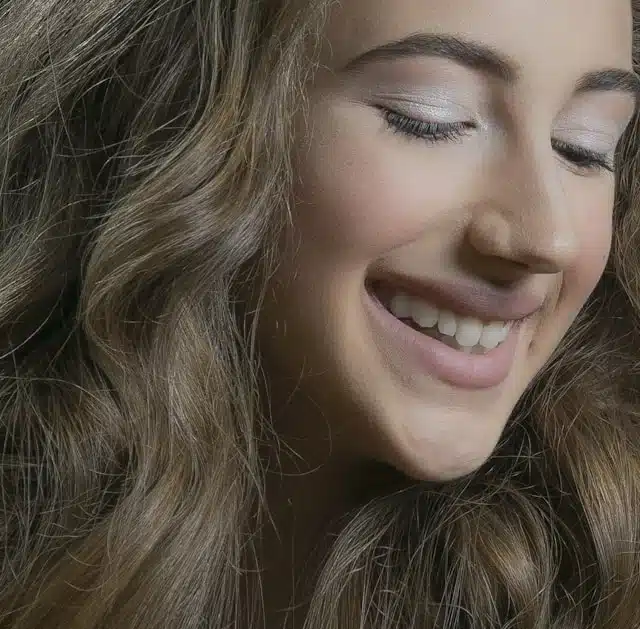 smiling woman with thick, voluminous hair after hair regrowth treatment