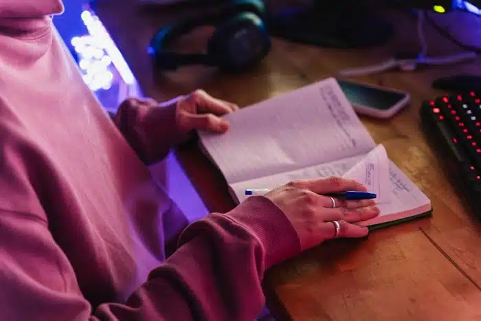 person writing fanfiction in a notebook at home