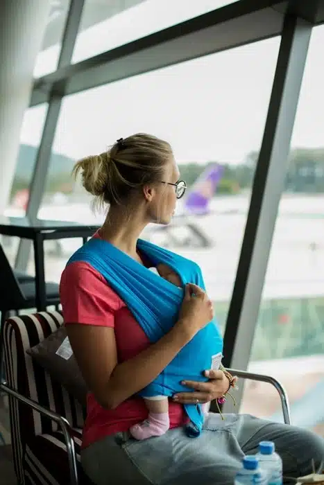 mom wearing a baby carrier at the airport with planes visible in the background