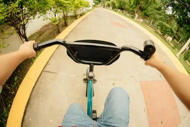 person learning how to ride a tricycle on a paved park path