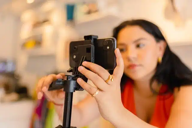 female creator setting up her phone on a tripod for a streaming session indoors