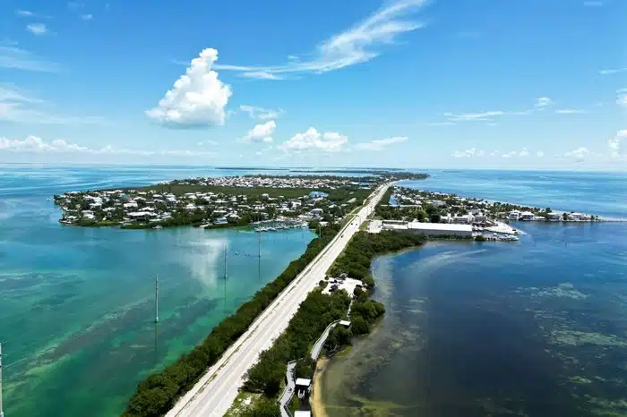 Aerial view of a vacation island in the Florida Keys with turquoise waters, a coastal highway, and rental homes along the shoreline