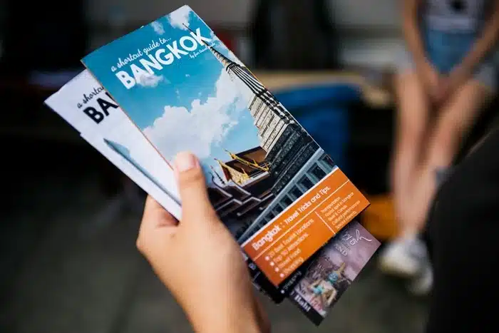 a hand holding Bangkok travel guide brochures with tips and top tourist attractions
