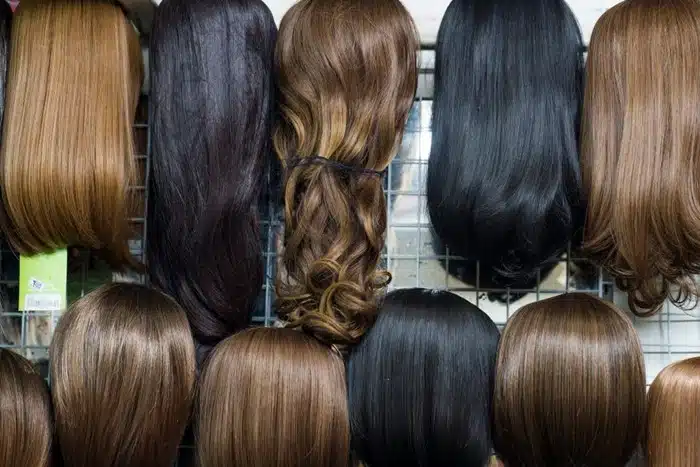 Variety of straight bob wigs in black and warm brown shades arranged on mannequin heads in a wig shop