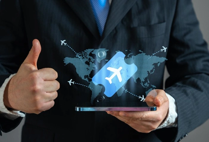 Businessman holding a tablet with a digital flight ticket and world map graphic, giving a thumbs up for managed business travel