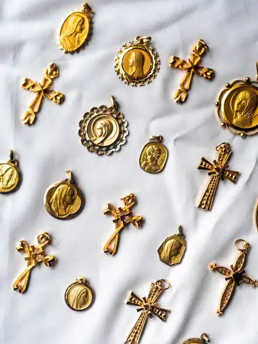 collection of gold virgin mary pendants and cross charms on a white fabric background