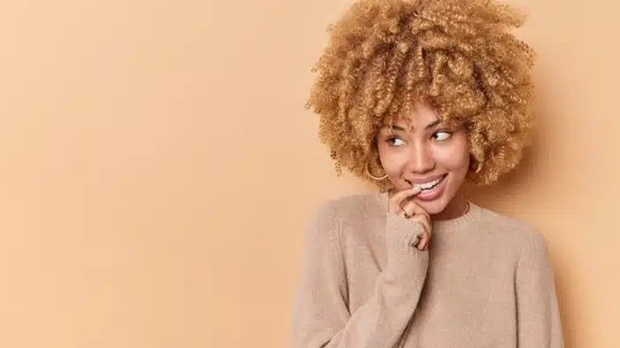 Woman wearing a voluminous curly bob wig in golden blonde tones