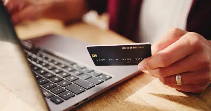 person holding a credit card in front of a laptop highlighting cybersecurity safety when banking overseas