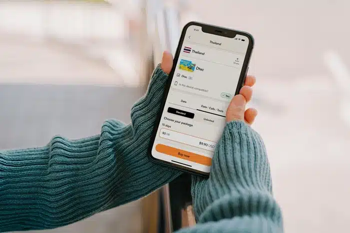 hands holding a smartphone displaying an esim for traveling in asia app with a Thailand package selected