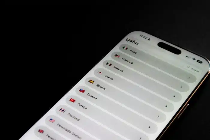 Smartphone displaying the Yoho eSIM app with a list of countries and flags for international data plans