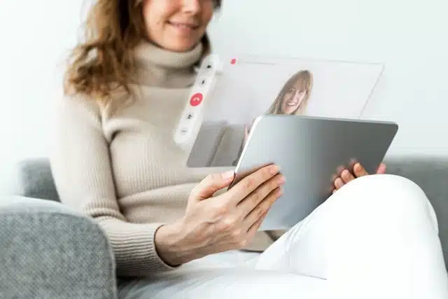 woman sitting on a couch having a video call on a tablet with a stable fiber optic internet connection