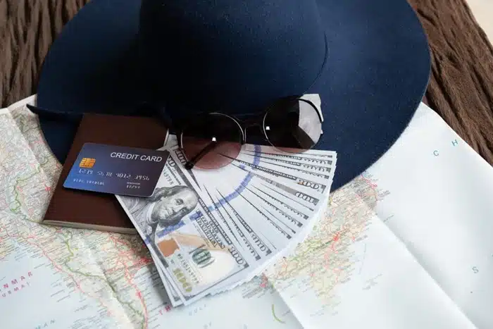 financial management abroad — travel hat, credit card, passport, cash, and map on a wooden surface