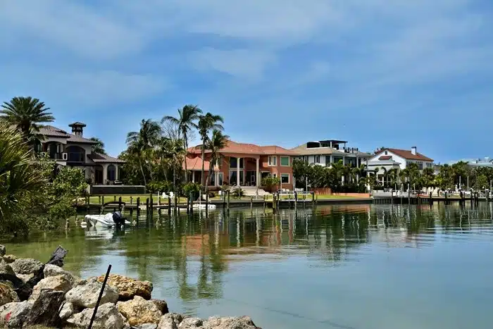 Waterfront homes with private docks and boats along a calm canal in Sarasota, Florida on a sunny day