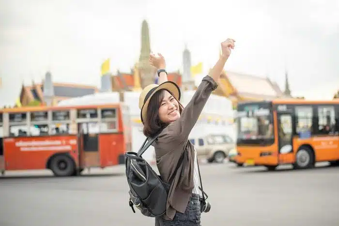 why spontaneous travel makes you happier — woman celebrating with arms raised in Bangkok