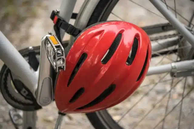 red safety helmet resting on a tricycle wheel and pedal