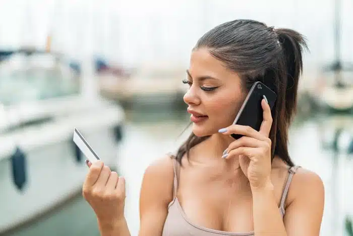 Woman holding a card and talking on her phone at a marina