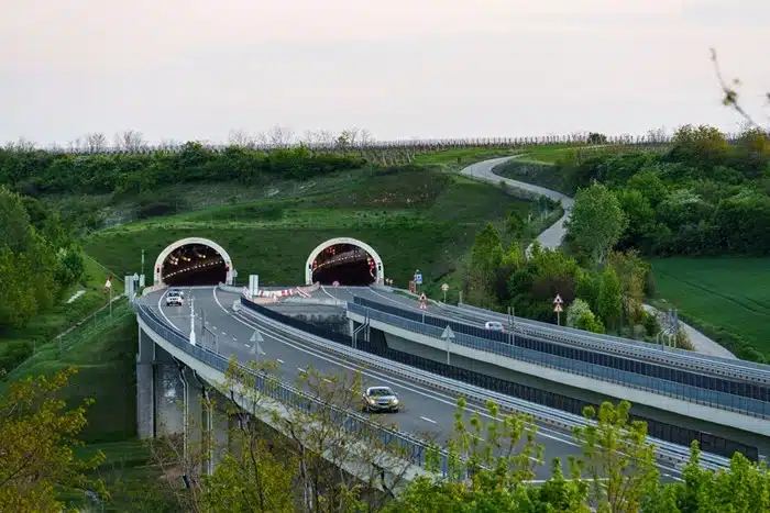 The M6 highway in Hungary with twin tunnel entrances cutting through a green hillside at dusk