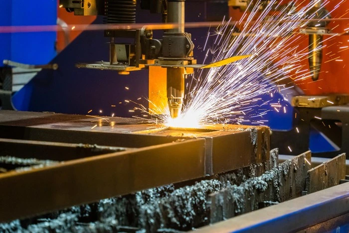 hypertherm vs. lincoln electric plasma cutter cutting thick metal plate with bright sparks in an industrial fabrication setting