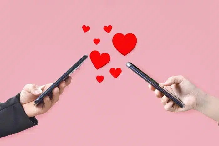 two people exchanging hearts through their phones representing online dating connection