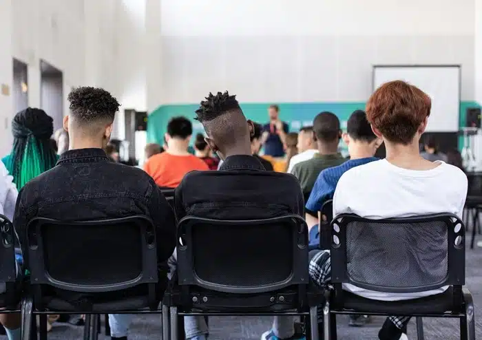 Diverse international students attending a university lecture from behind in a modern classroom